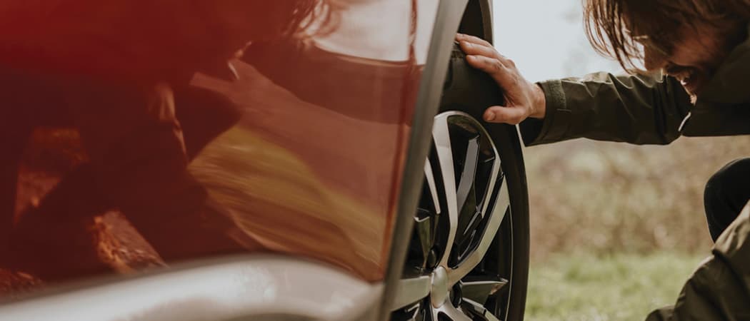 Man looking at car tire and checking condition of tire